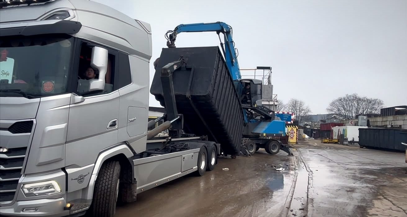 Abrollcontainer wird per Umschlagbagger beladen